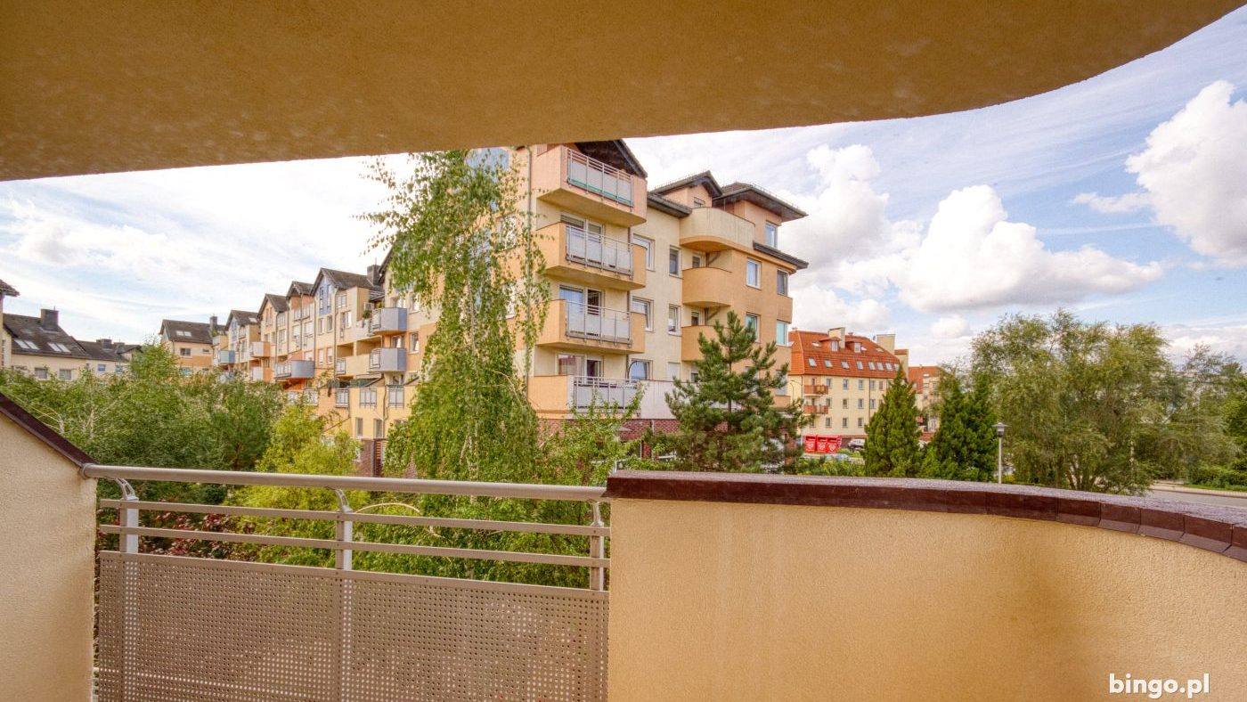 Widok z balkonu mieszkania na kamienice i zieleń